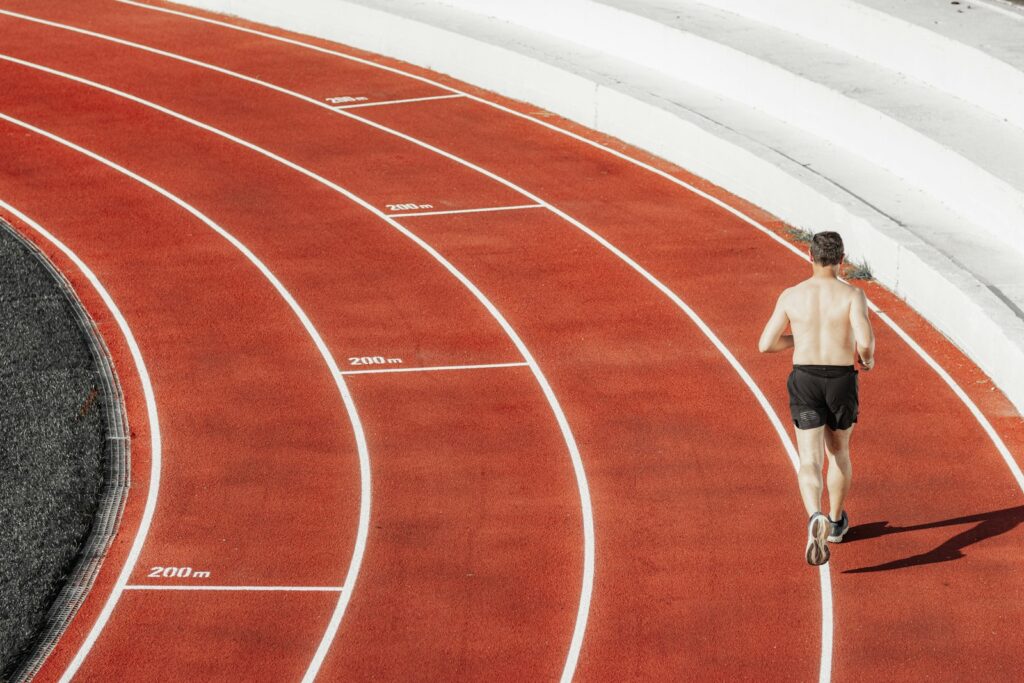 Läufer in der Kurve einer roten Tartanbahn beim Tempotraining für 10 km unter 50 Minuten
