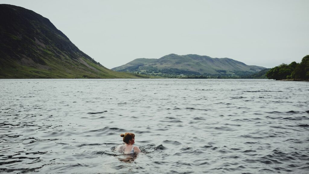 Frau schwimmt ruhig in einem See vor Bergkulisse