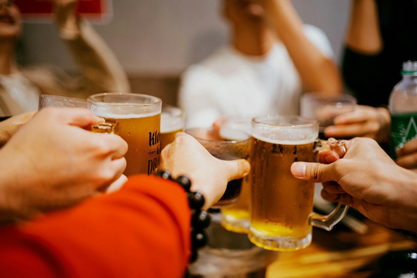 Freunde stoßen mit Biergläsern an, Symbolbild für Alkohol und Muskelaufbau