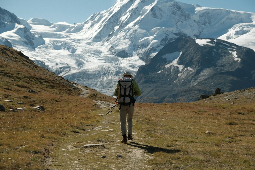 Wanderer mit Rucksack steigt vor schneebedeckten Gipfeln am Gornergrat auf