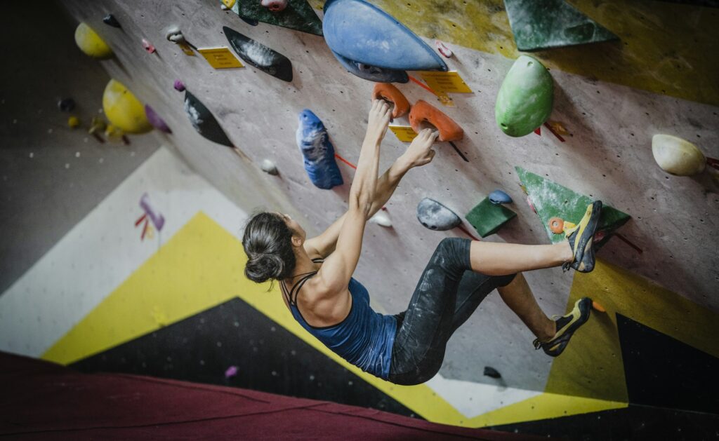 Frau beim Bouldern an einer Kletterwand in einer Halle
