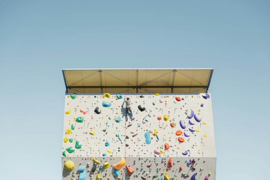 Bouldern Schwierigkeitsgrade: Person klettert an einer bunten Boulderwand im Freien