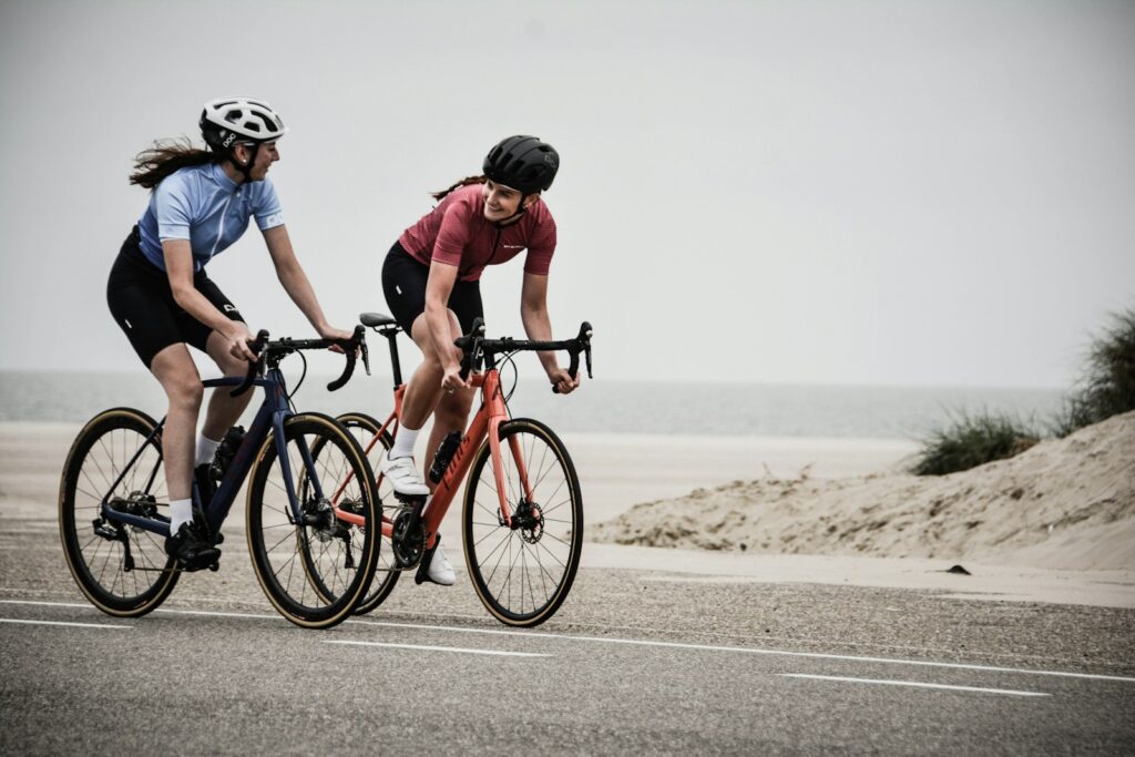 Zwei Radfahrende auf Rennrädern auf einer Straße am Meer