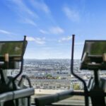 Zwei Ellipsentrainer vor einer großen Fensterfront mit Blick auf eine Stadt