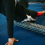 Mann rollt Hüfte und Oberschenkel auf einer Faszienrolle