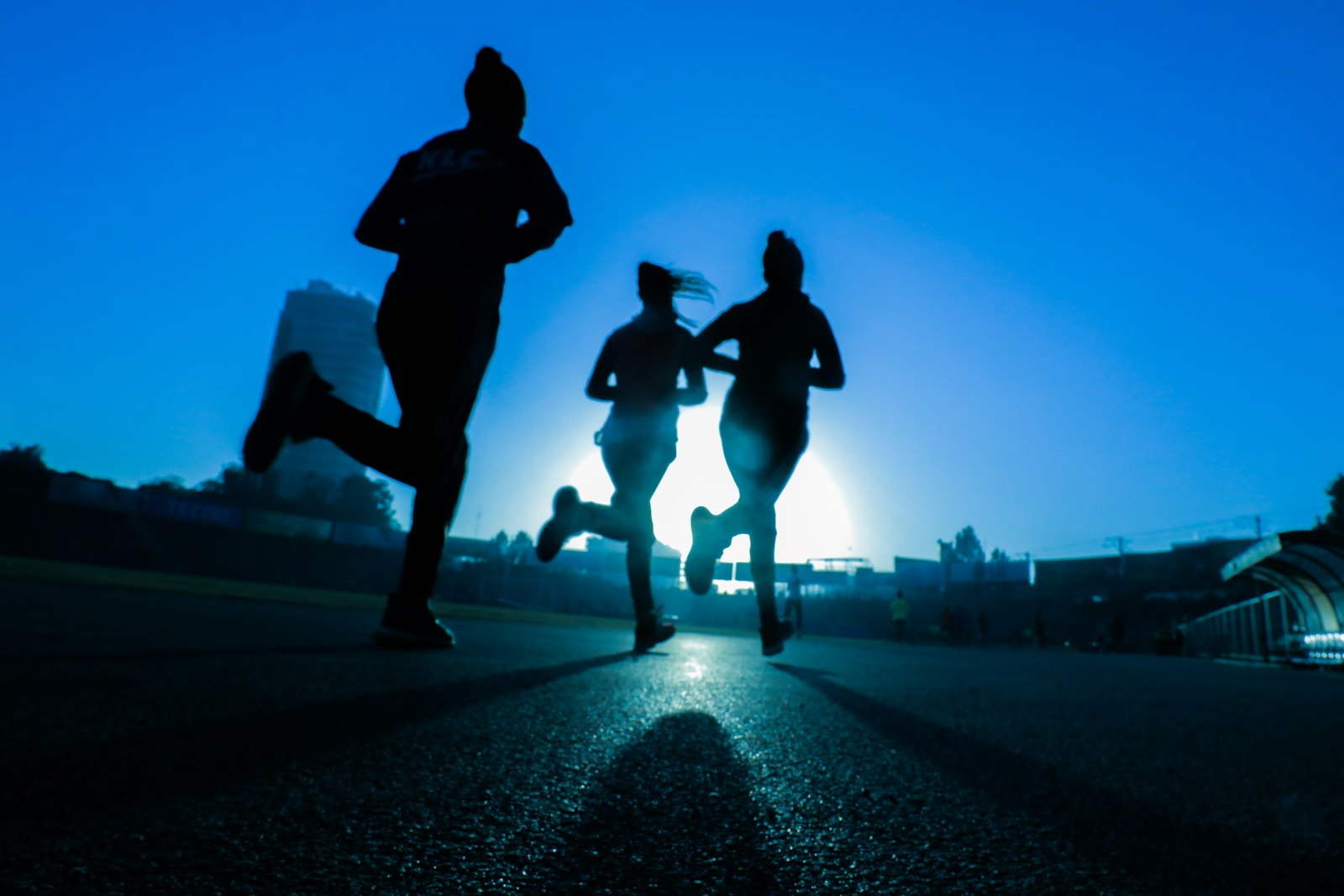 Drei Läuferinnen als Silhouetten auf der Straße beim Training für die Halbmarathon Distanz