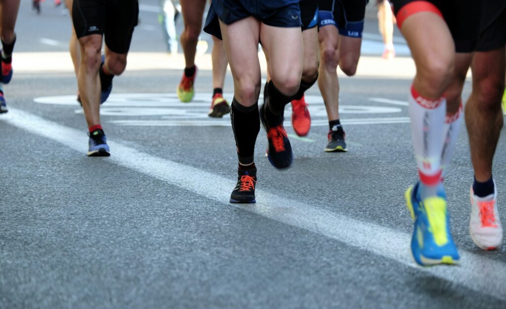 Läufergruppe auf einer Asphaltstraße bei einem Volkslauf, für den ein Halbmarathon-Trainingsplan vorbereitet