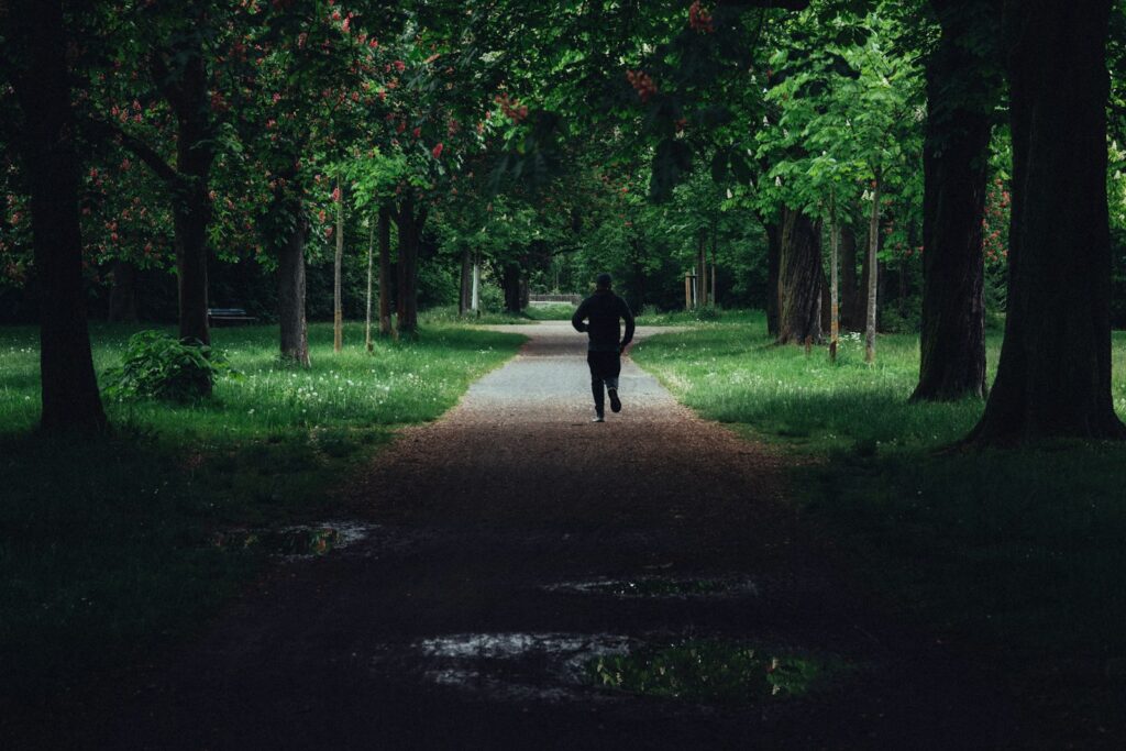 Person läuft im ruhigen Tempo auf einem Weg durch einen grünen Park