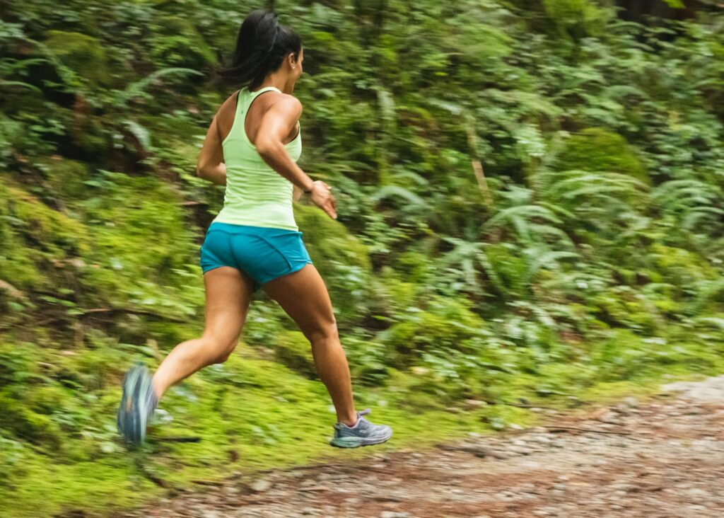 Joggen Vorteile in der Natur: Läuferin auf einem Waldweg bei Tageslicht