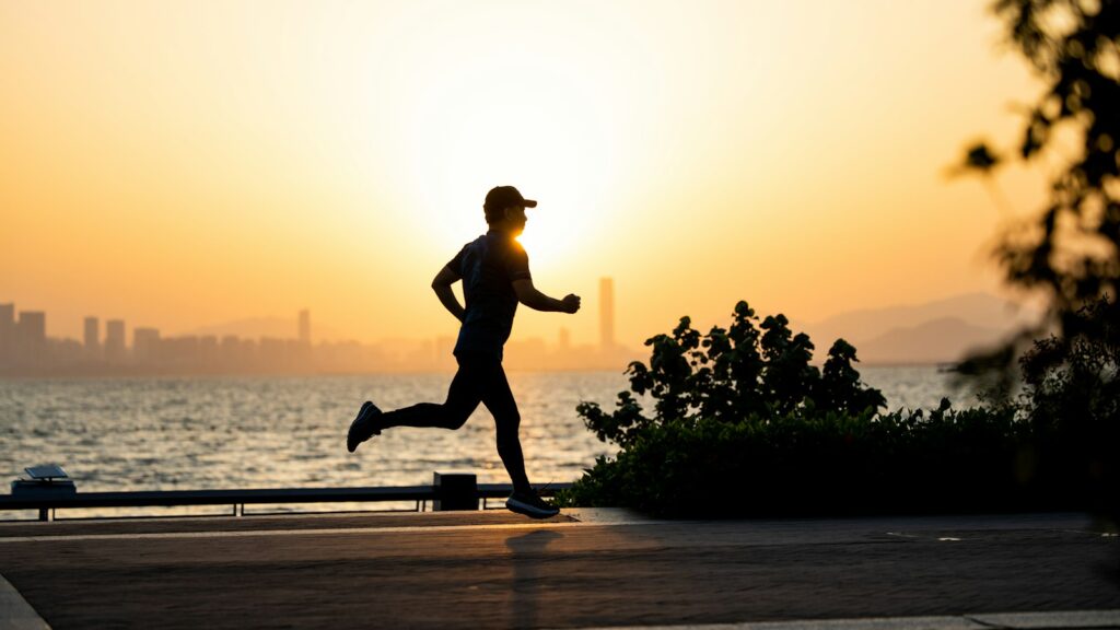 Läufer joggt bei Sonnenuntergang an einer Uferpromenade