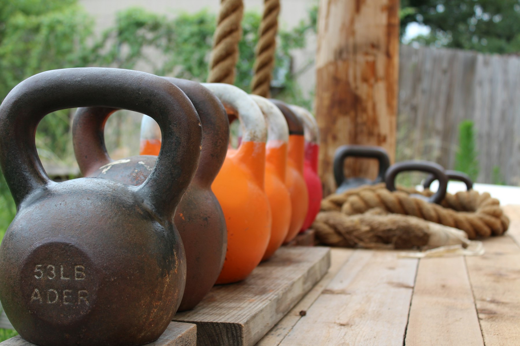 Reihe Kettlebells verschiedener Größe auf Holz zeigt die Stufen beim Kettlebell-Gewicht