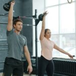 Mann und Frau trainieren gemeinsam den Kettlebell Swing mit Kettlebells