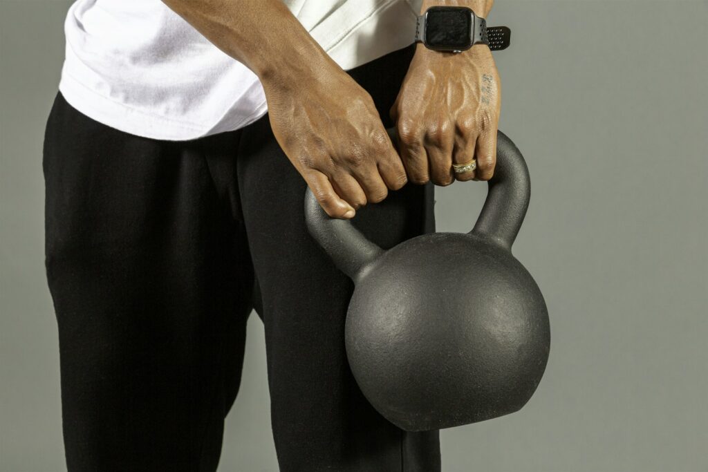 Mann hält eine Kettlebell mit beiden Händen am Griff vor dem Körper