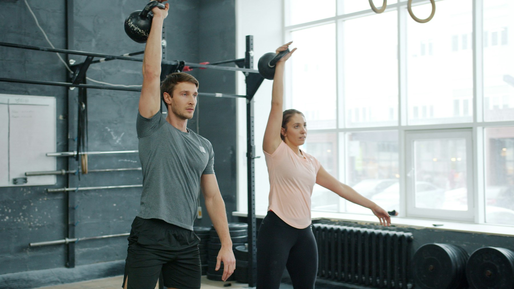 Mann und Frau trainieren gemeinsam den Kettlebell Swing mit Kettlebells