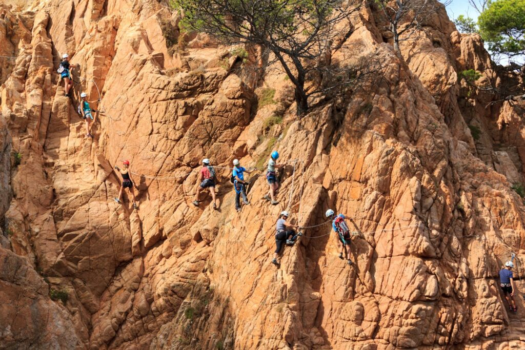 Gruppe auf einem Klettersteig an einer Felsklippe über dem Meer bei Sonnenschein