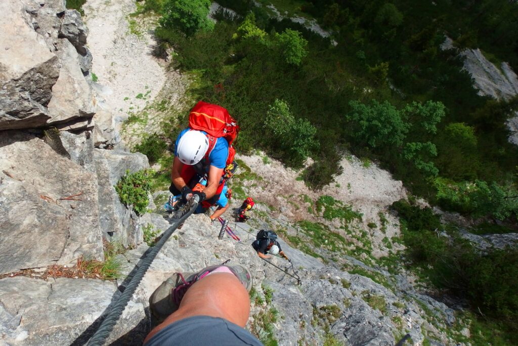 Gruppe mit Helm und Klettersteigset an einer Felswand: Klettersteig Schwierigkeitsgrade richtig einschätzen