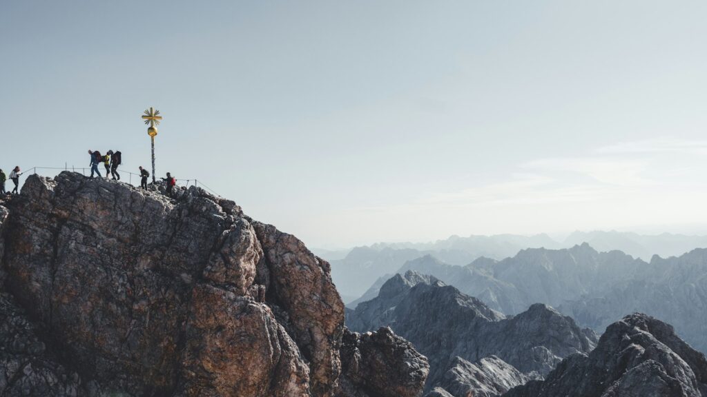 Bergsteiger auf einem Felsen im Zugspitzgebiet mit Blick über die Gipfel, Sinnbild für Klettersteige Deutschland