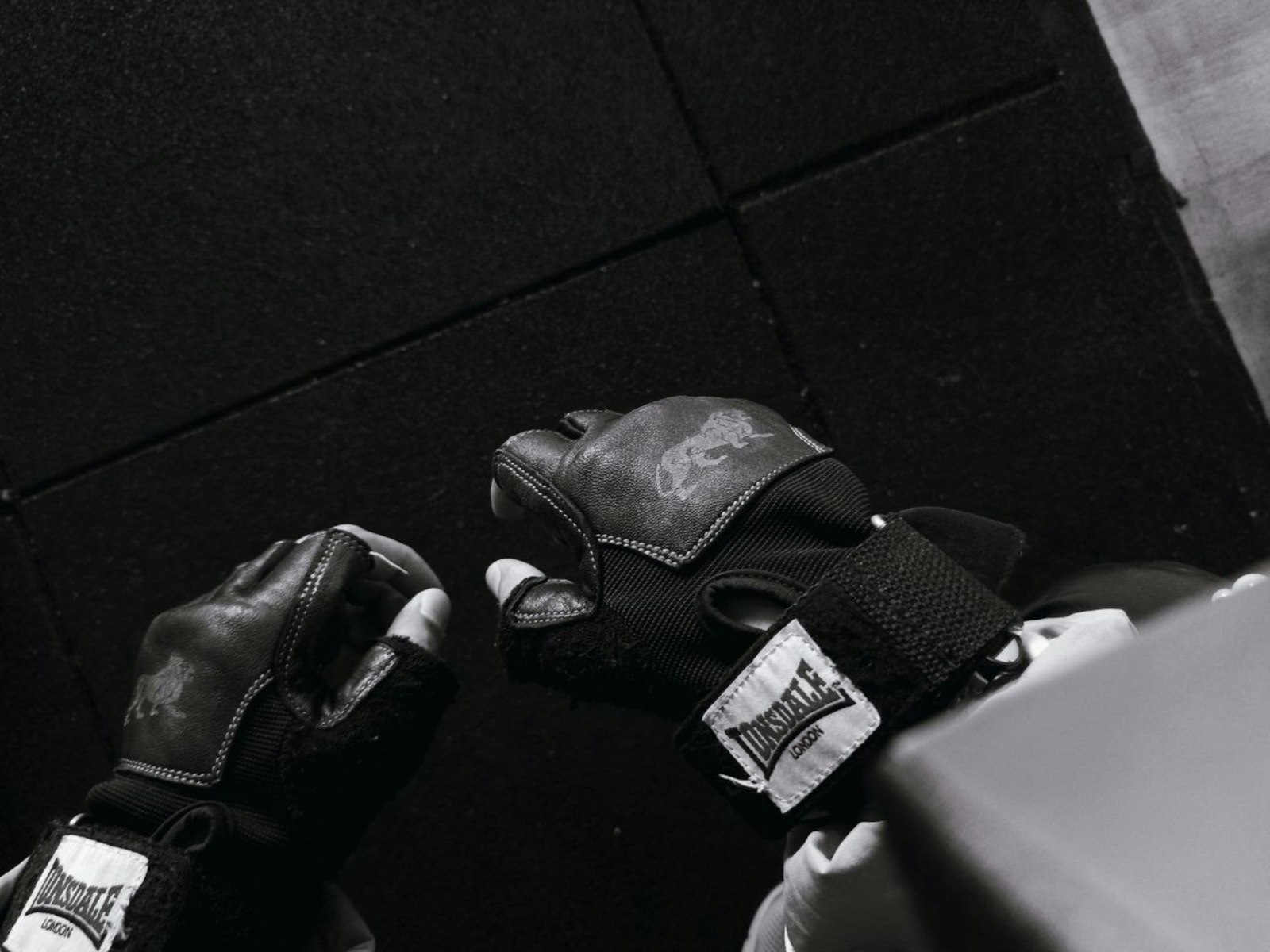 Hände mit fingerlosen schwarzen Krafttraining-Handschuhen aus Leder mit Handgelenkband