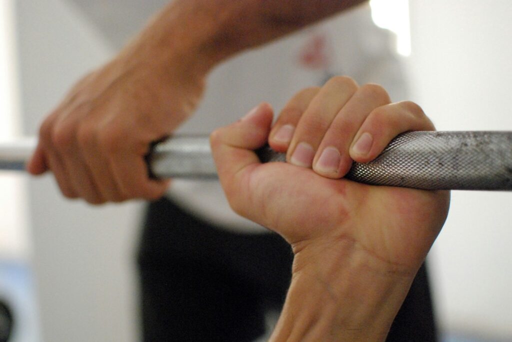 Hände umgreifen ohne Krafttraining-Handschuhe fest eine Langhantelstange