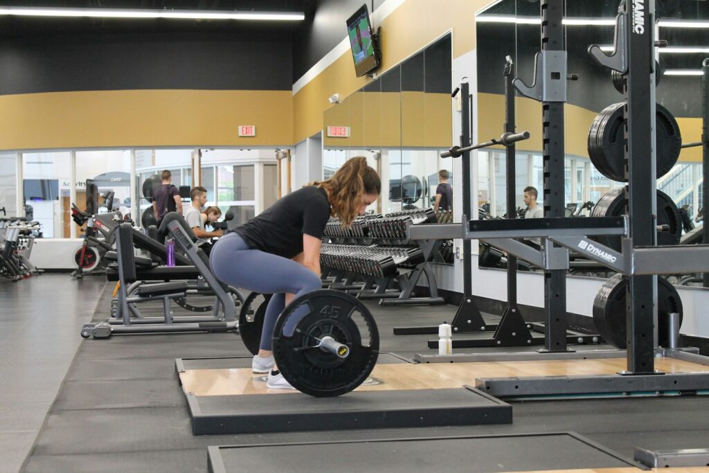 Frau hebt im Fitnessstudio eine beladene Langhantel beim Kreuzheben