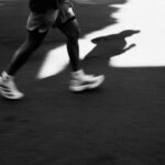 Beine einer laufenden Person in Laufschuhen mit langem Schatten, Fußbewegung und Pronation im Abrollen