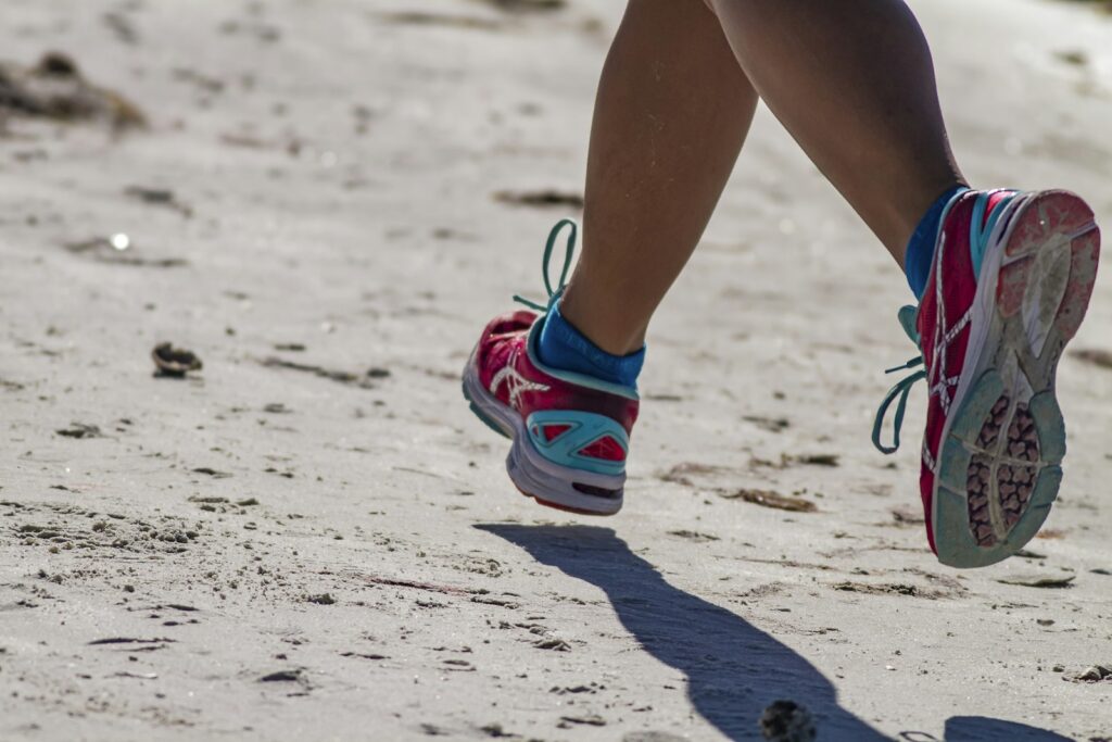 Läuferin in vollem Schritt am Strand, der Fuß setzt auf und rollt mit natürlicher Pronation ab
