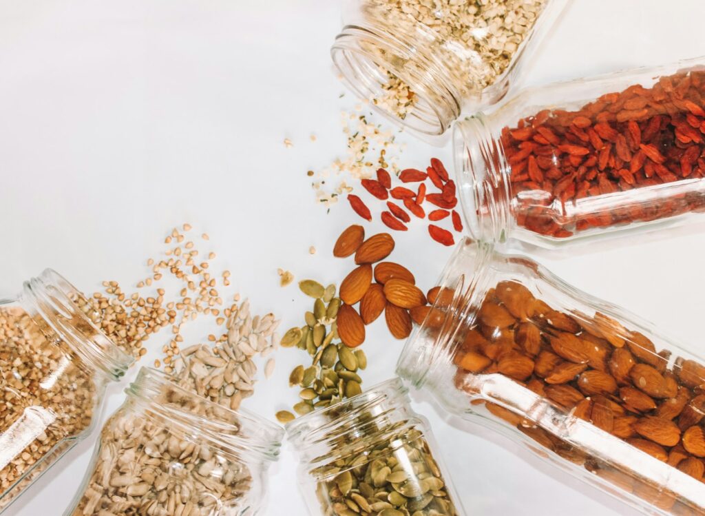 Gläser mit Hülsenfrüchten, Haferflocken, Nüssen und Samen als natürliche Quellen für Magnesium bei Muskelkater
