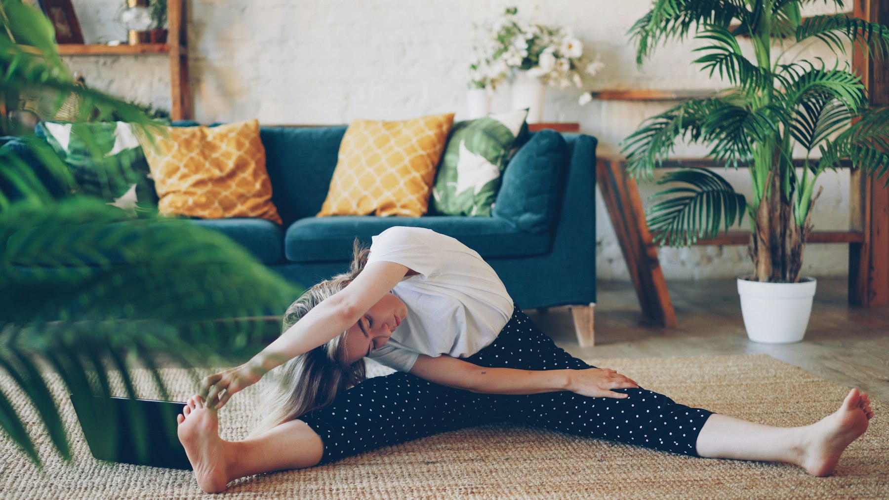 Frau macht im Wohnzimmer ihre Mobility-Routine mit Mobilisationsübungen auf dem Boden