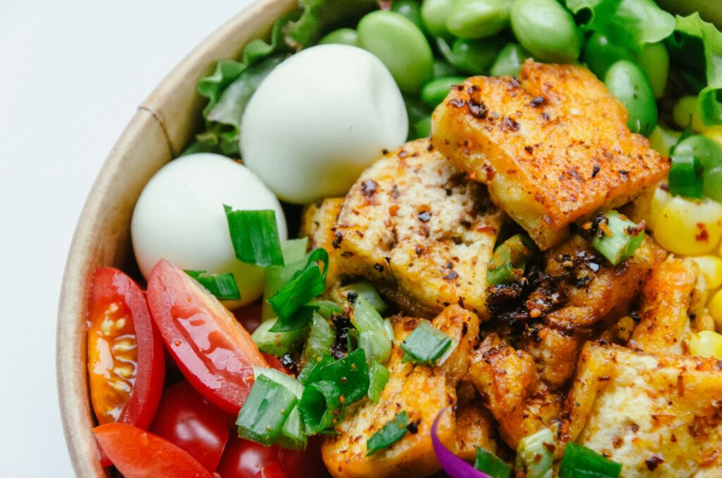 Bowl mit gekochten Eiern, Tofu, Bohnen und Gemüse als Kombination proteinreicher Zutaten