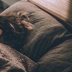 Frau schläft entspannt im Bett, Morgenlicht fällt durchs Fenster, Schlaf und Regeneration