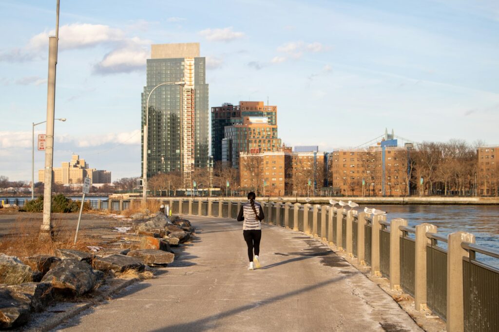 Läuferin joggt im lockeren Tempo auf einem Uferweg in der Stadt, um Seitenstechen vorzubeugen
