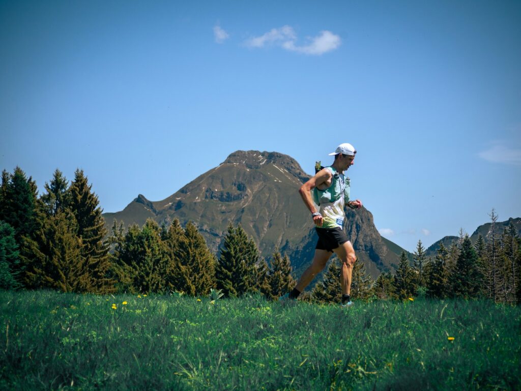Trailrunner mit Trailrunning-Rucksack auf einem sonnigen Bergweg