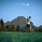 Trailrunner mit Trailrunning-Rucksack auf einem sonnigen Bergweg