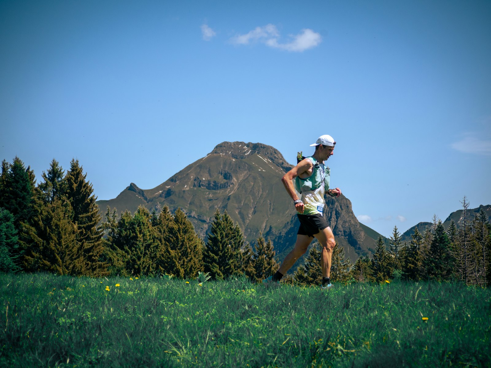 Trailrunner mit Trailrunning-Rucksack auf einem sonnigen Bergweg