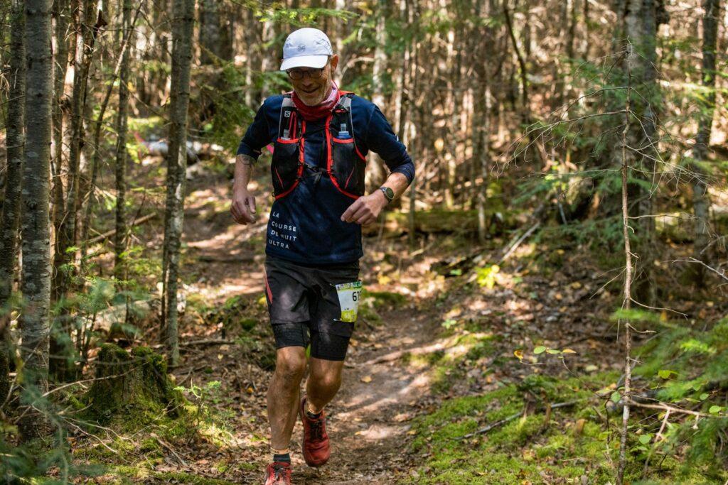 Läufer mit Trailrunning-Rucksack auf einem Waldpfad