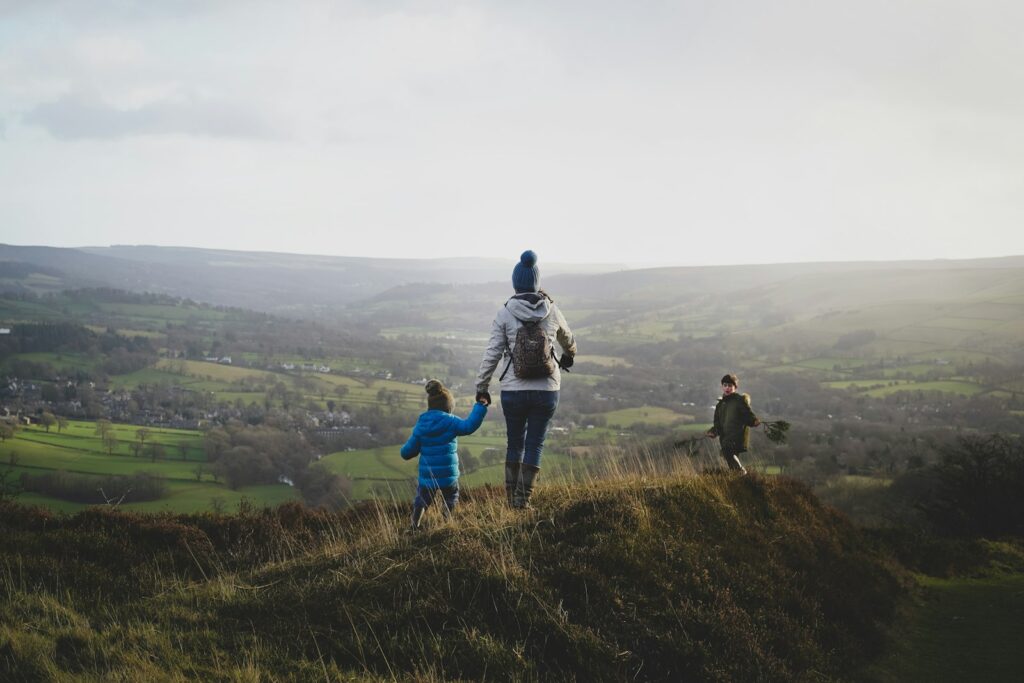 Wanderung mit Kindern: Mutter und Kind gehen einen grasbewachsenen Hügel hinauf