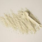 Whey Isolate: zwei Messlöffel mit hellem Proteinpulver auf weißem Hintergrund