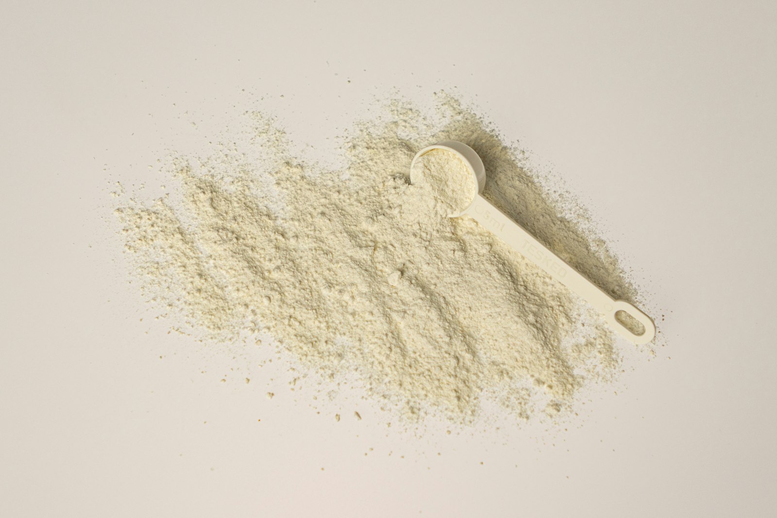 Whey Isolate: zwei Messlöffel mit hellem Proteinpulver auf weißem Hintergrund