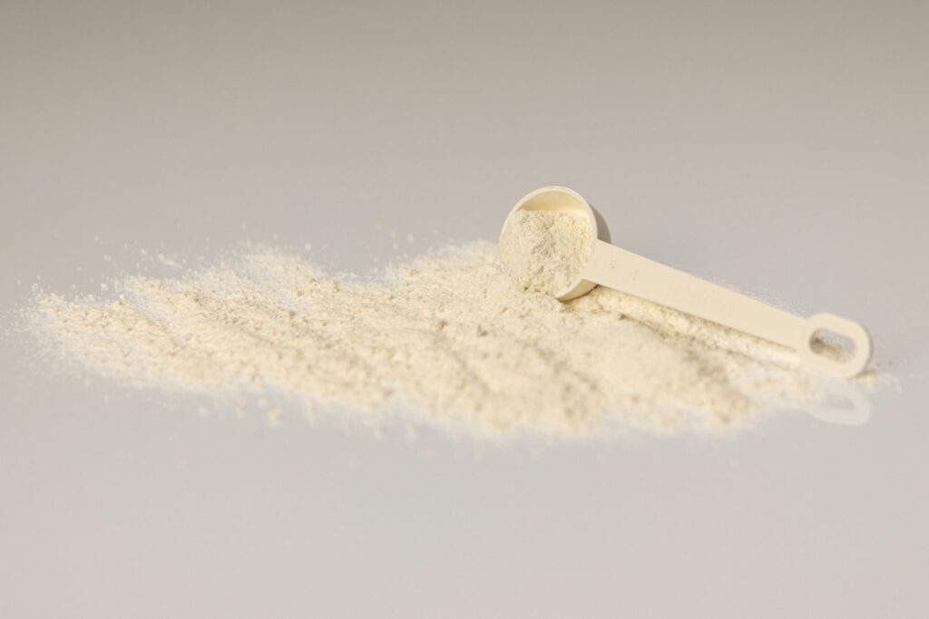 Whey Isolate als helles Proteinpulver mit Messlöffel